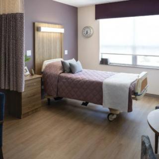 A modern hospital room with a single bed and minimalistic decor.
