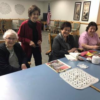 A group of elderly women gathered around a table, enjoying a recreational activity together.