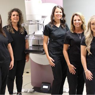 Dedicated healthcare team in front of a mammography machine, promoting women's health.