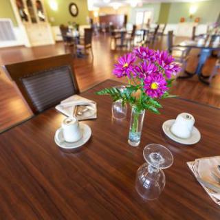 A cozy dining area featuring a beautifully arranged table with flowers and coffee cups.