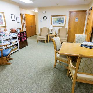 A well-furnished waiting room with chairs, a table, and artwork on the walls.