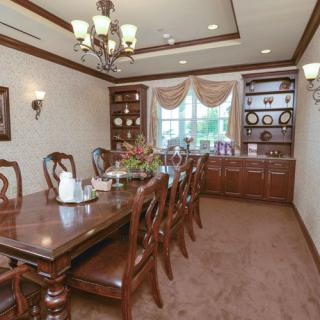 An elegant dining room featuring a long wooden table, ornate chairs, and a classic chandelier.
