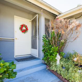 A welcoming entrance with a decorated wreath on the front door, surrounded by greenery.