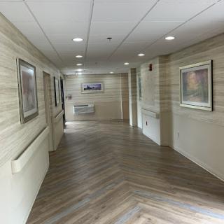 A well-lit hallway featuring wooden flooring and framed artwork on the walls.