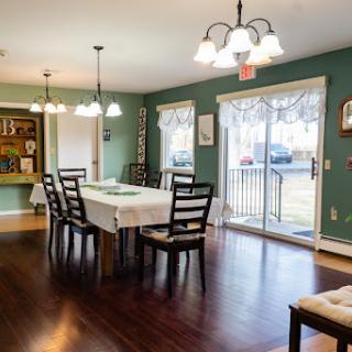 A cozy dining room featuring a green color scheme, a large table, and comfortable chairs, perfect for family gatherings.