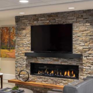 A modern living room with a stone wall fireplace and mounted TV, complemented by warm lighting.