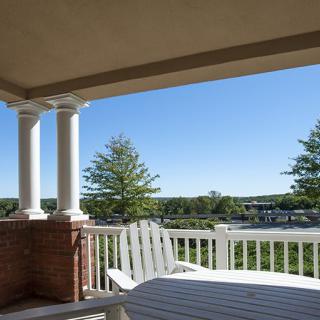 A peaceful porch with seating overlooking a scenic view on a clear day.