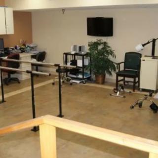 A rehabilitation room equipped with parallel bars and various therapy tools.
