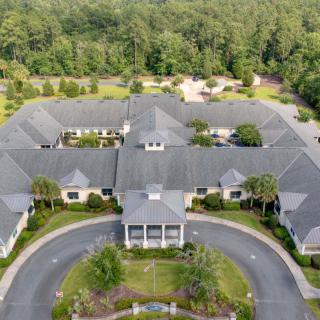 Aerial view of a large residential building surrounded by trees and landscaping.