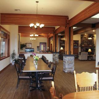 A spacious, rustic dining area featuring wooden beams and elegant chandeliers.