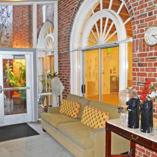 A cozy hotel lobby featuring brick walls, a comfortable couch, and decorative arched windows.