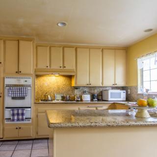 A spacious kitchen with wooden cabinets and a granite countertop.