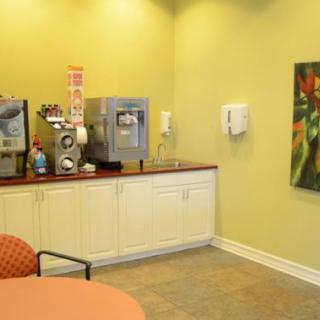 A waiting room with a beverage station, featuring a coffee machine and seating.