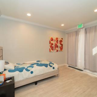 A minimalist bedroom with a bed, artwork on the wall, and soft lighting.