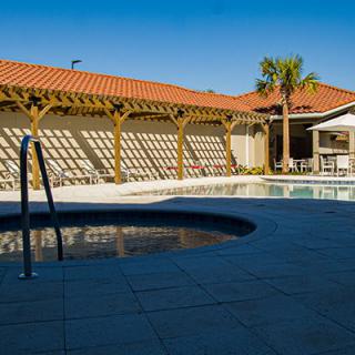 A serene outdoor pool area with a tiled patio and wooden pergola, perfect for relaxation and leisure.