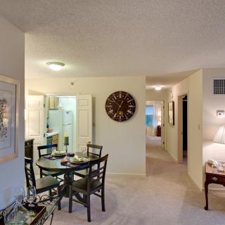 A cozy apartment interior featuring a dining table, kitchen, and living area.