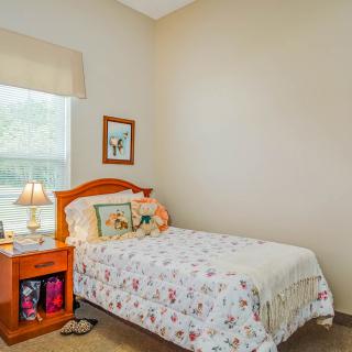 A cozy bedroom with a single bed, nightstand, and window.