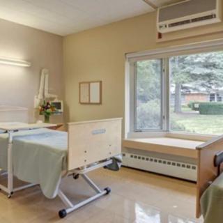 A hospital room with a bed, large window, and basic medical equipment.
