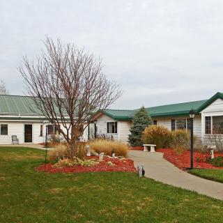A picturesque view of a single-story building surrounded by a manicured lawn and landscaped gardens.