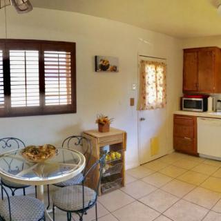 A cozy kitchen with a small dining area featuring a round table and chairs, framed by wooden cabinets and natural light.