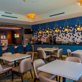 A stylish and modern restaurant interior featuring blue walls, cozy seating, and warm lighting.