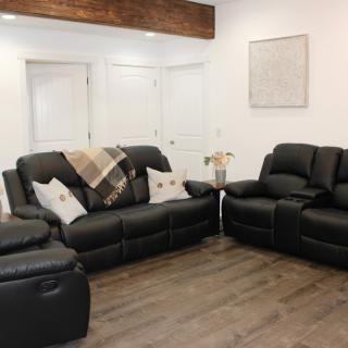 A cozy living room with black leather reclining sofas and modern dcor.