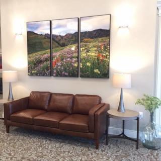 A cozy living room with a leather sofa, wall art, and modern lamps.
