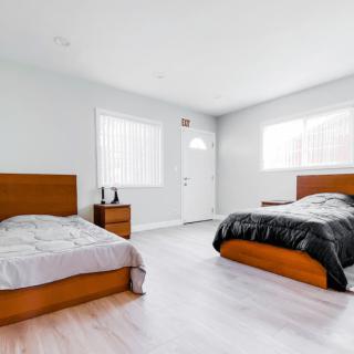 A minimalist bedroom featuring two wooden beds with light and dark bedding, complemented by bright natural lighting and white walls.