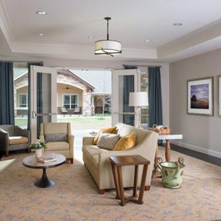 A modern, cozy living room with neutral colors and natural light coming through open doors.