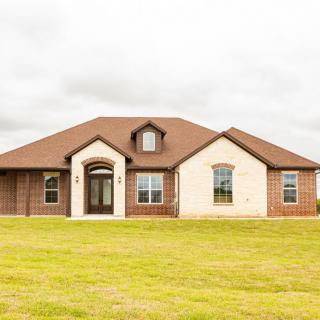 A modern brick suburban house with a large front lawn.