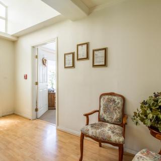 A cozy interior with a wooden chair, framed pictures on the wall, and a view into an adjacent room.