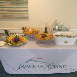 A buffet table set up at Savannah Grand, featuring a selection of fruits, snacks, and beverages.