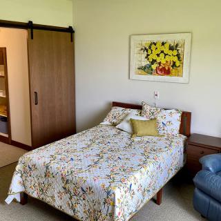 A cozy bedroom featuring a bed with floral bedding, artwork on the wall, and a closet with a sliding door.