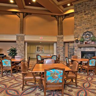 A cozy dining area with wooden tables and chairs, a fireplace, and warm decor.