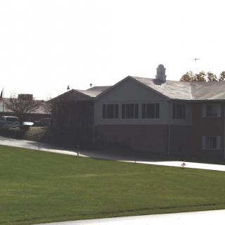 A view of a building set against a grassy landscape.