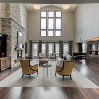 Spacious living room with high ceilings and large windows, featuring modern furniture and a stone fireplace.