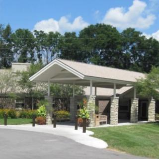 A building entrance with a covered walkway surrounded by trees and landscaping.