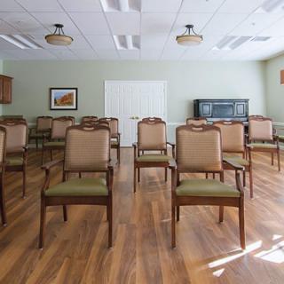 An empty meeting room with arranged chairs on a wooden floor.