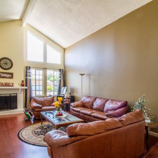 A cozy living room featuring leather sofas, a fireplace, and a vaulted ceiling.