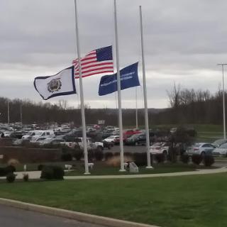 Flags at half-mast in a parking area on a cloudy day.