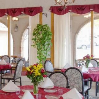 A cozy restaurant interior with elegantly set tables and floral arrangements.
