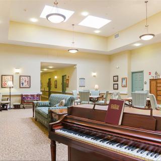 A spacious living room with a piano and comfortable seating arrangements.