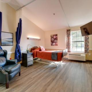 A well-lit hospital room with a bed, a comfortable chair, and decorative elements.
