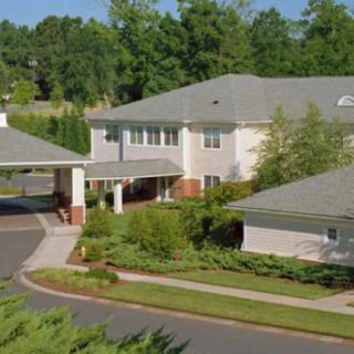 A residential building surrounded by trees with a driveway in front.