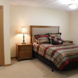 A cozy bedroom with a neatly made bed, nightstand, and lamp.
