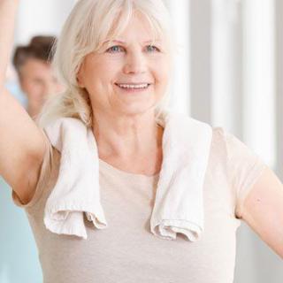 Elderly woman smiling during a fitness class.