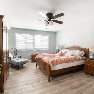 A bright and airy bedroom featuring a wooden bed, ceiling fan, and modern decor with natural light streaming through the windows.