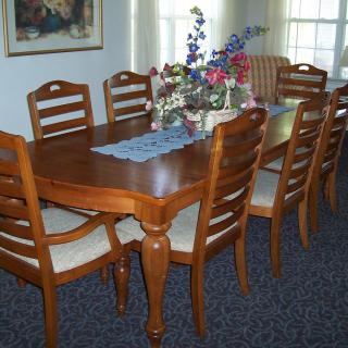 A well-arranged dining room featuring a wooden table with matching chairs and a floral centerpiece.