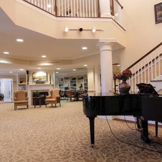A spacious lobby area featuring a grand piano, comfortable seating, and an elegant staircase.