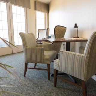 A well-lit office space with a wooden table and several upholstered chairs.